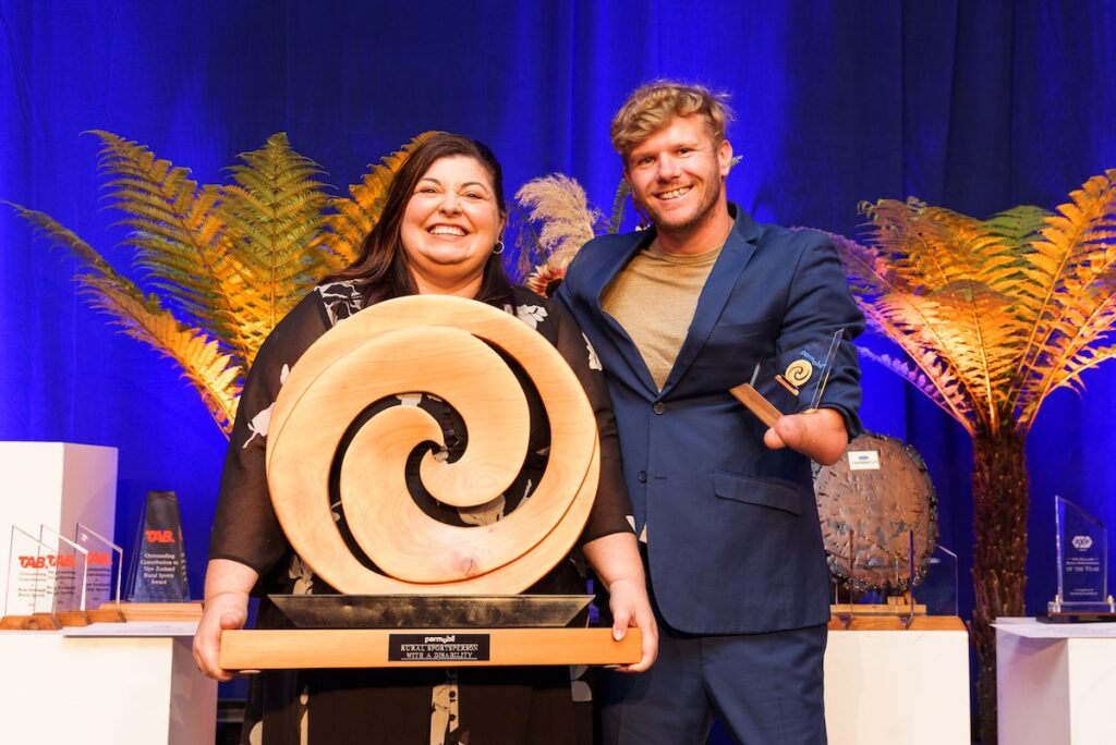 Susie Ballantyne Director of Permobil with Paralympian Cameron Leslie MNZM accepting the award on Adam Hall's behalf